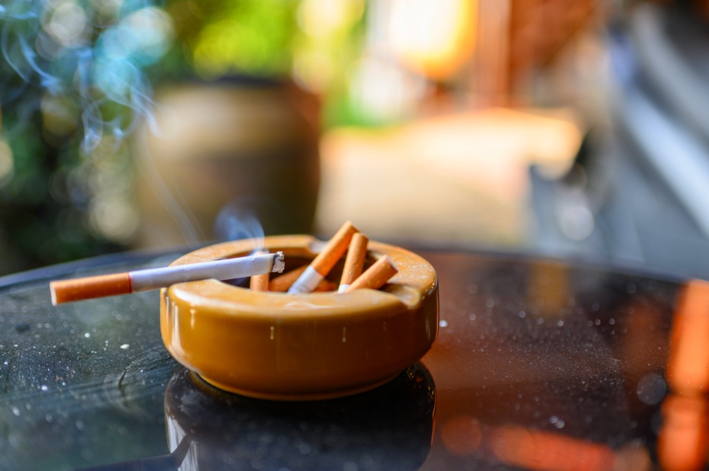 cigarette burning in an orange ashtray