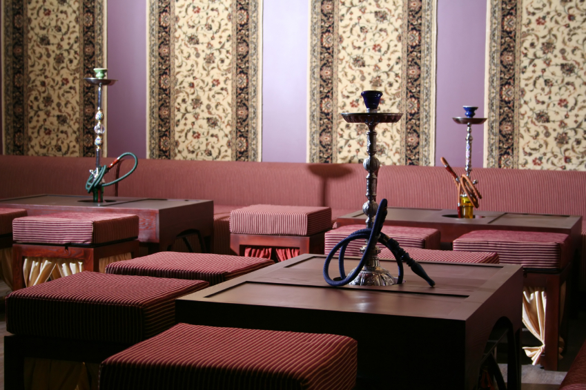 3 waterpipes stand on tables in a brightly decorated room