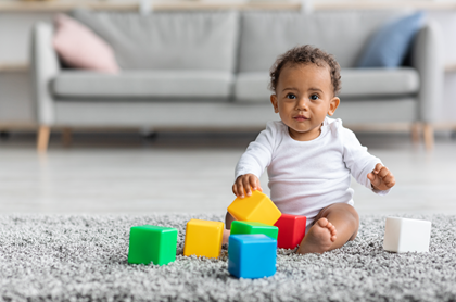 baby sitting on carpet playing with blocks