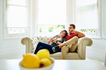 man smoking and woman pregnant sitting on the couch
